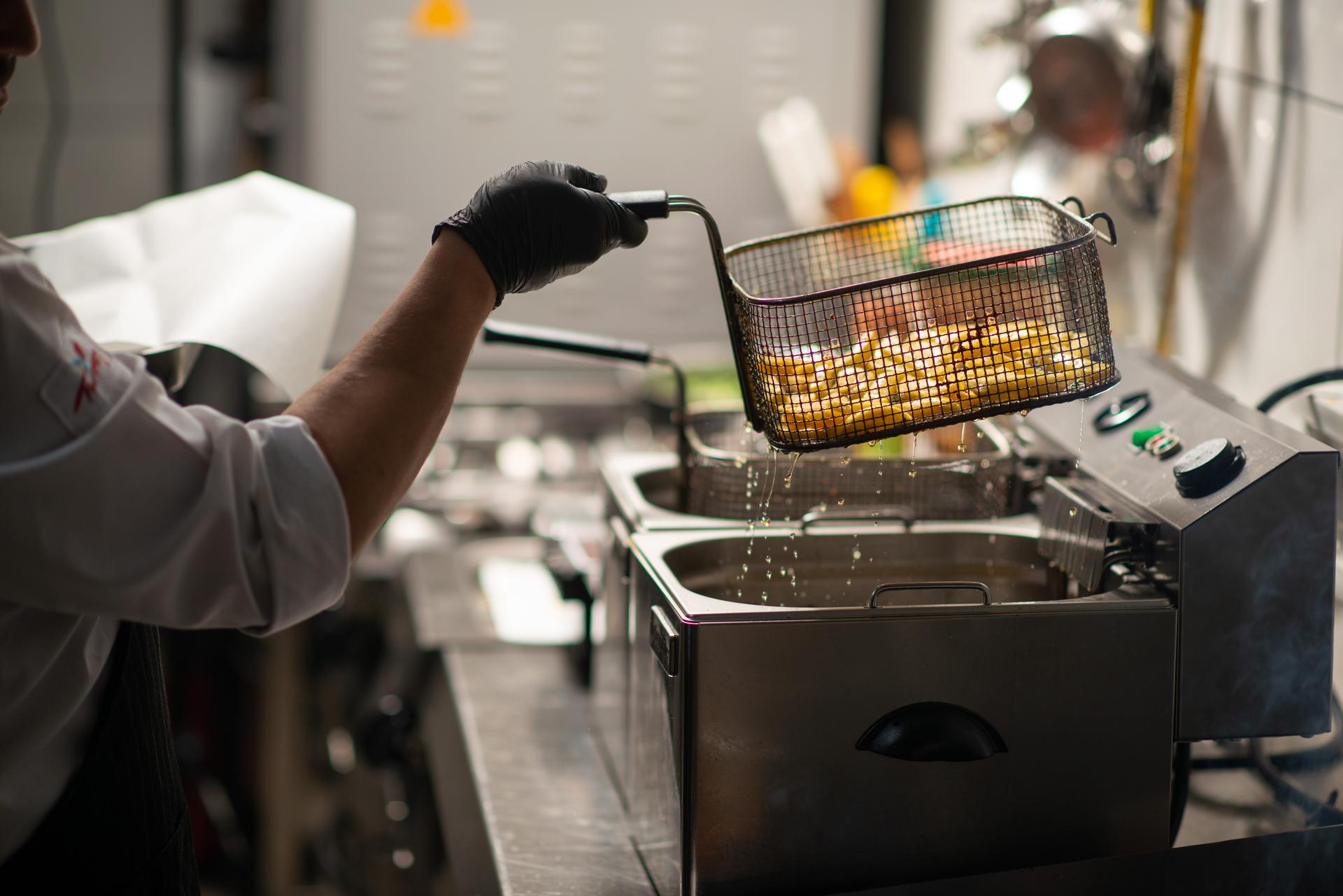 Chef frying potatoes in restaurant kitchen